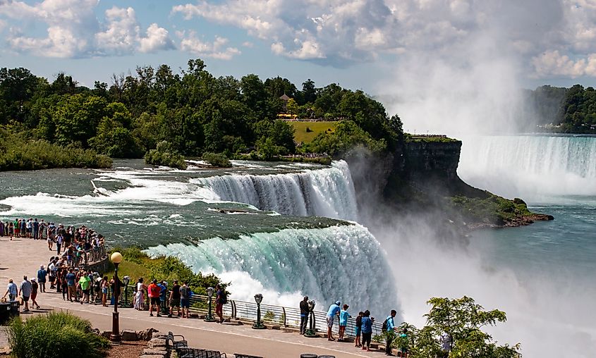 A group of people standing at the base of the waterfalls in Niagara Falls New York State Park.