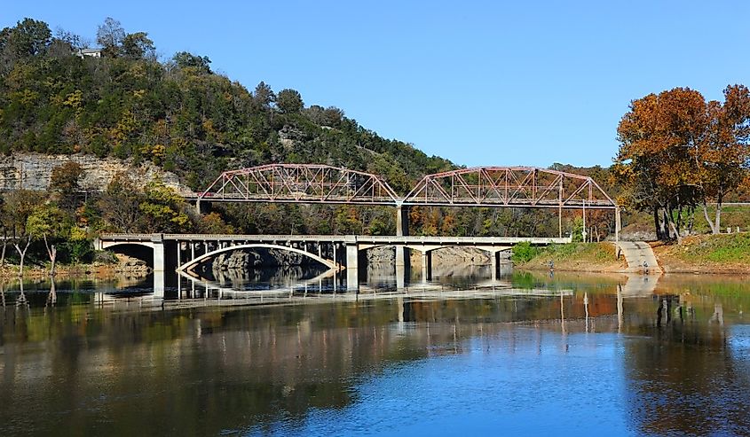 River Run Park on beautiful Bull Shoals Lake has two early fishermen. Reflection of the two bridges are mirrored in the quiet waters of the lake.