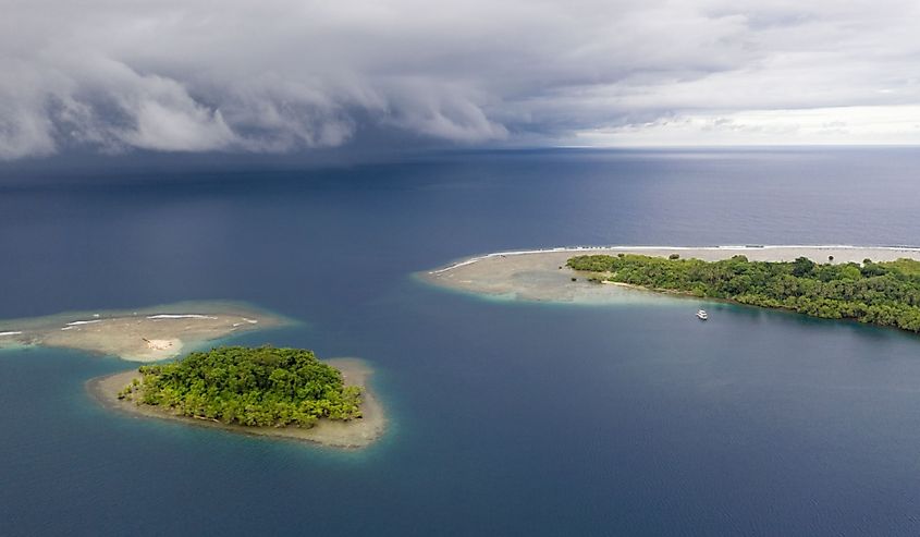 Rain clouds sweep over the Pacific Ocean approaching small, tropical islands in Papua New Guinea. 