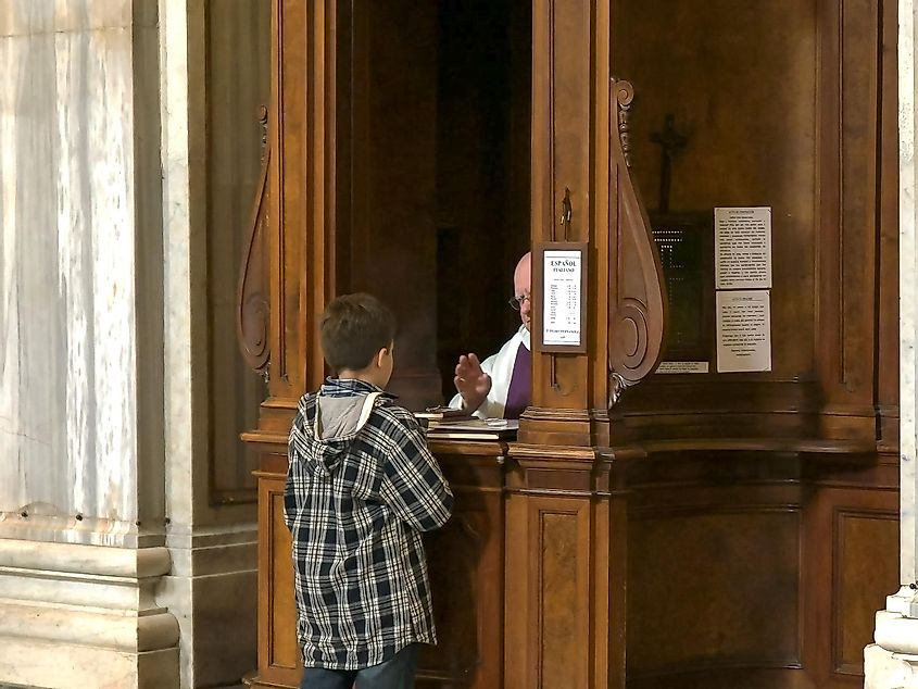 boy performing catholic confession at the basilica santa maria maggiore, rome