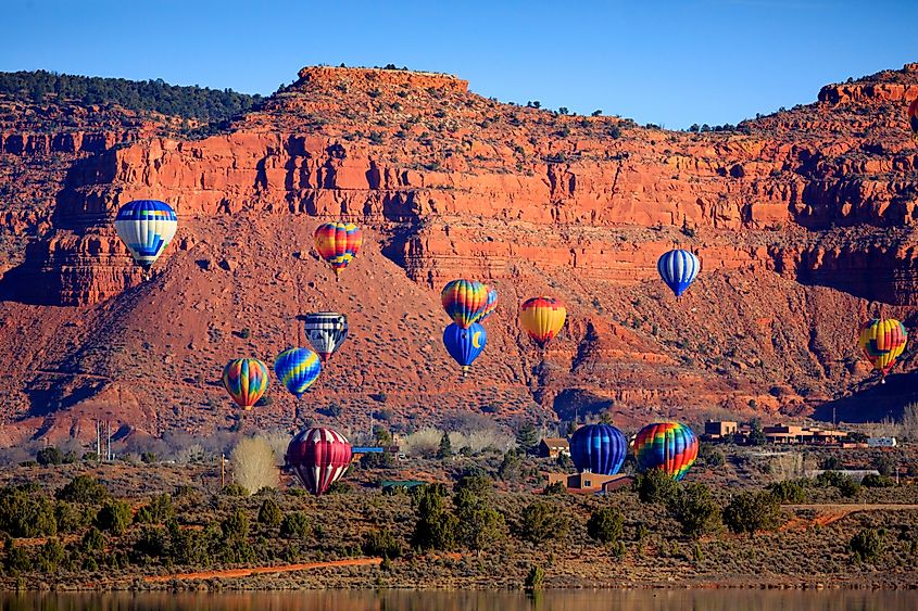 Colorful hot air balloons float against a backdrop of majestic red rock cliffs under a clear blue sky, conveying a sense of freedom and adventure.