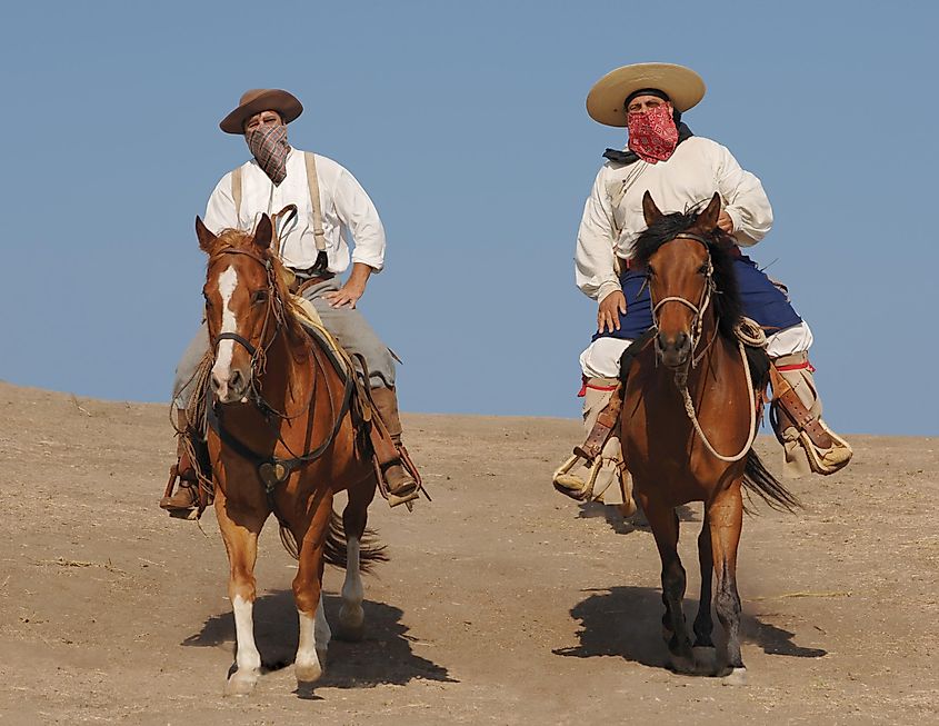 Two banditos riding on horses.