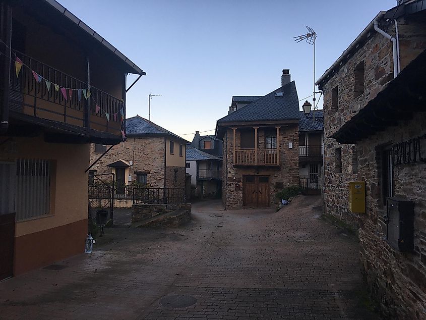 A street leading through a sleepy Spanish town with shuttered stone houses.