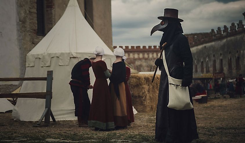 A masquerade historical scene reconstruction. Plague doctor in medieval old town