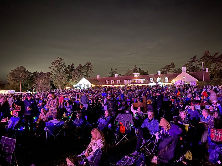 An evening festival crowd seated in camping chairs on the grass.