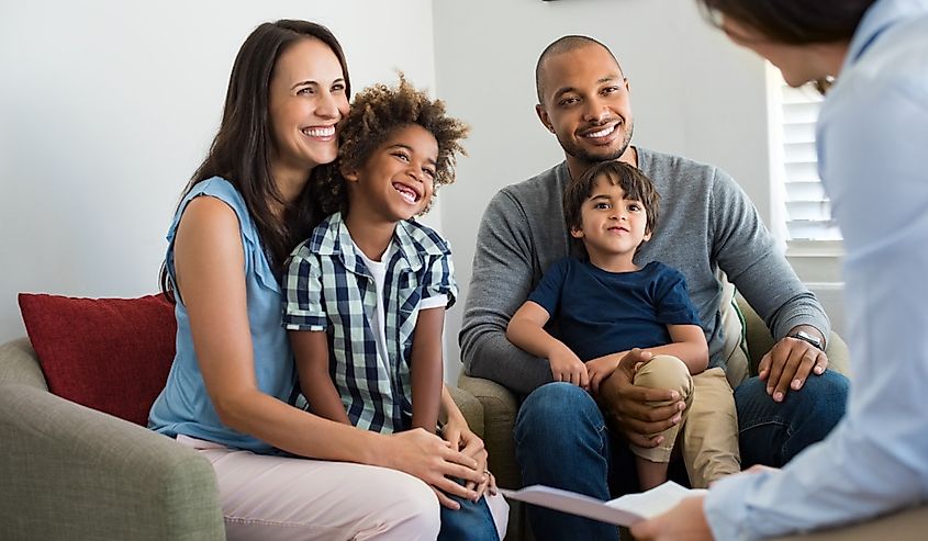 Smiling parents with adopted children discussing with counselor.