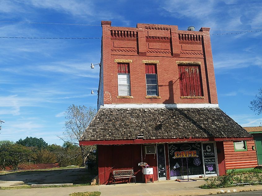 Old red brick building with awning by the roadside in Ada, Oklahoma.