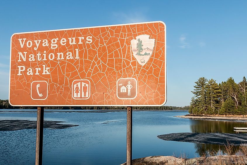 Landscape of Voyageurs National Park in northern Minnesota with a park sign in the foreground and trees and water in the background