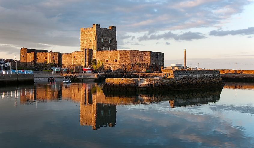 Medieval Norman Castle in Carrickfergus, Northern Ireland, and its reflection in water at sunset.