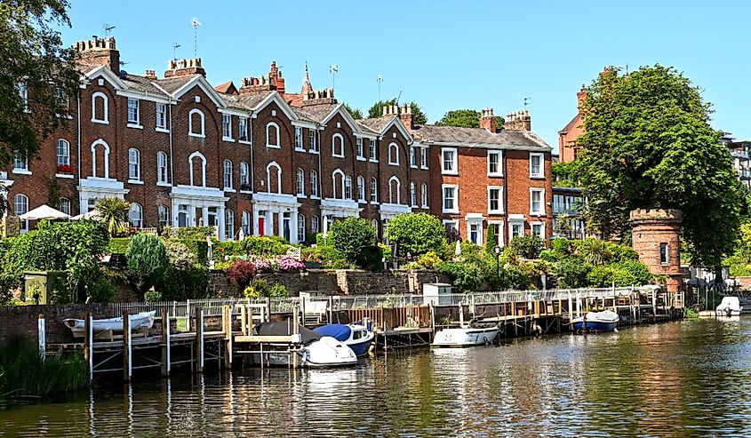 Small boats moored outside the back of houses on the River Dee. The river runs through the center of Chester