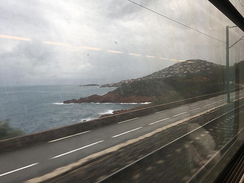 The seaside view out the window of a moving train. 