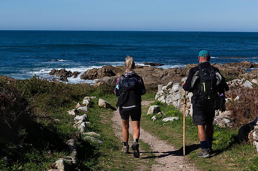 Two pilgrims walk the Portuguese Camino de Santiago along the coast in A Guarda