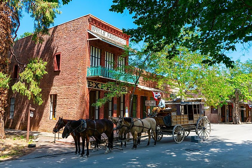 Horse-drawn stagecoach ride awaits passengers near a preserved historic building in Columbia State Historic Park, Columbia, California, USA.