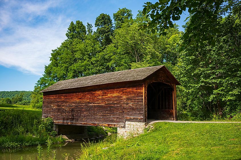 The Hyde Hall Covered Bridge, built in. 1825 and is the oldest existing covered bridge in the U.S., rests at the end of a dirt road during a summer day