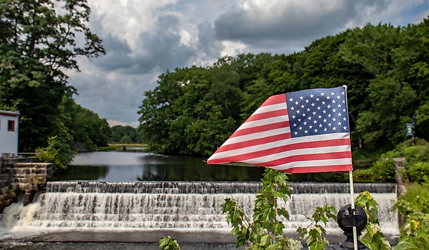 US flag on railing in front of Capron Falls, a waterfall in Uxbridge, Massachusetts