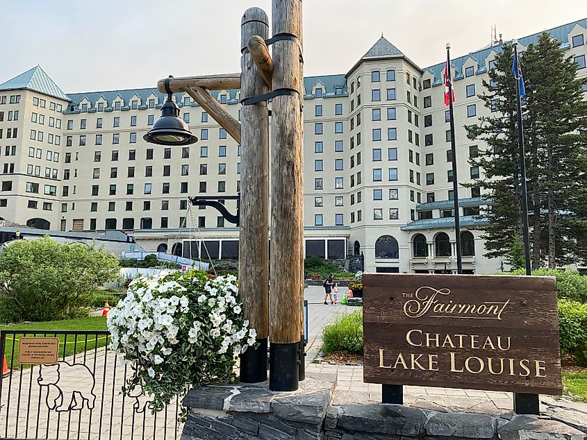 A wooden sign reading Fairmont Chateau Lake Louise introduces the massive historic hotel. 