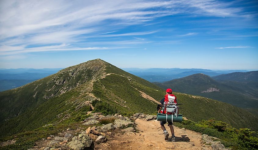 Hikers trekking along a mountain range, the Franconia ridge traverse, with a beautiful landscape background and blue skies on a sunny day