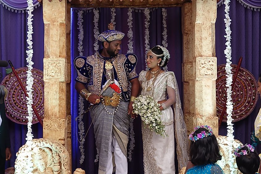 Wadduwa, Sri Lanka - May 11, 2018: Beautiful wedding ceremony in Sri Lanka. Newlyweds in traditional costumes stand under the arch. Wedding ceremony location with bride and groom
