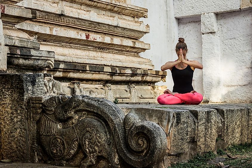 A woman practicing yoga in an ancient Indian temple.