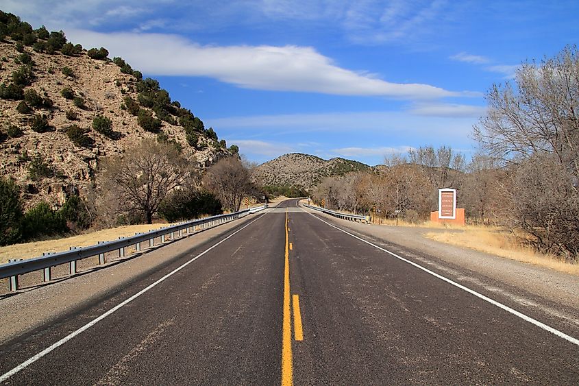 A scenic road passes through a mountainous desert landscape as it makes its way into the historic town of Lincoln, New Mexico.