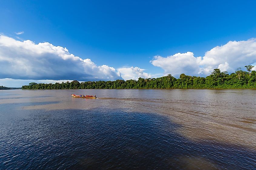 Cloud formation background with boat sailing along river on a sunny day. Rainforest landscape scenery in South America