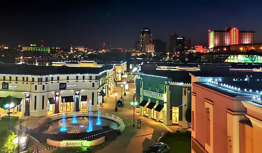 Fountains and stores at night at Louisiana Boardwalk Mall with Shreveport Skyline in background