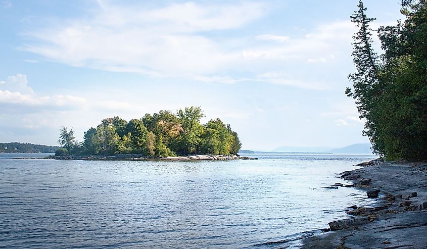 Small island in Lake Champlain Vermont with rocky shore in the foreground