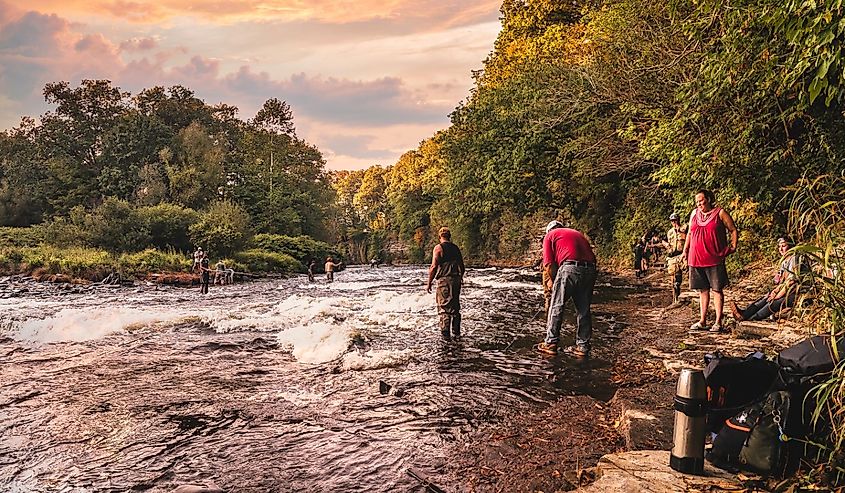 People are fishing at the Salmon River before sunset in Pulaski, New York.