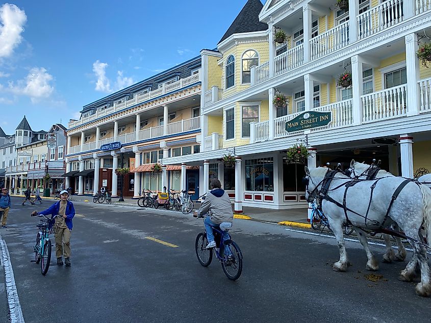 Cyclists and a horse-drawn carriage stroll past the Victorian Inns of Mackinac Island. 