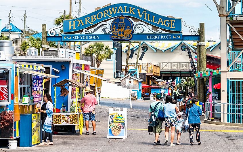 Sign for Harborwalk Village in Emerald Grande Coast in Florida Panhandle with people walking and shopping, buying food in cafe, street vendor restaurants