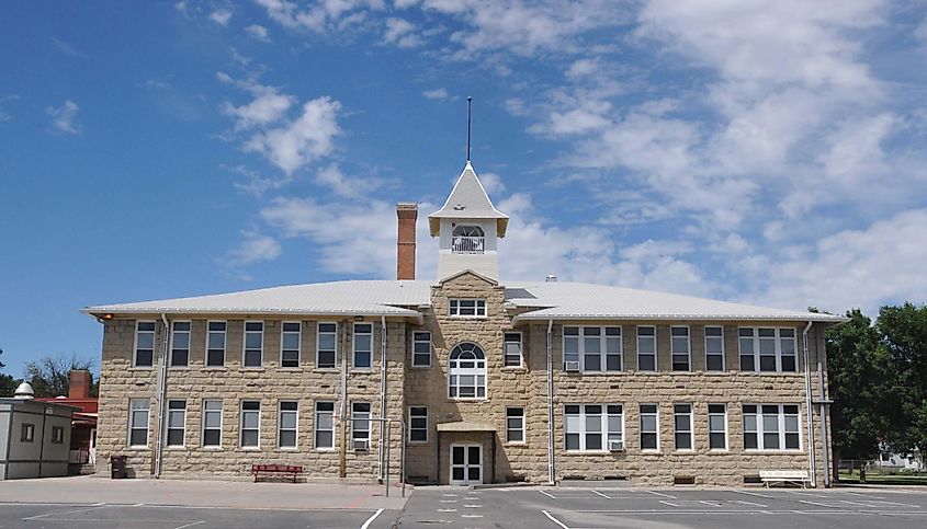 Roundup Central School in Roundup, Montana. Built in 1911, with the east wing added in 1913. The architects drew inspiration from Italian Renaissance and Romanesque styles, reflected in the building's overall symmetry, multi-paned arched center window, wide eaves, rough stone walls, and triangular parapet.