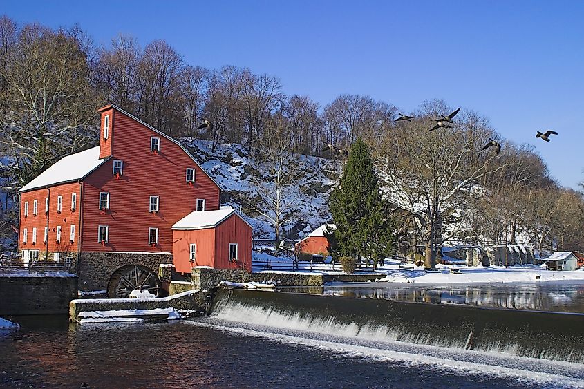 Clinton, New Jersey: Mill with snow-covered landscape, trees, and birds in flight.