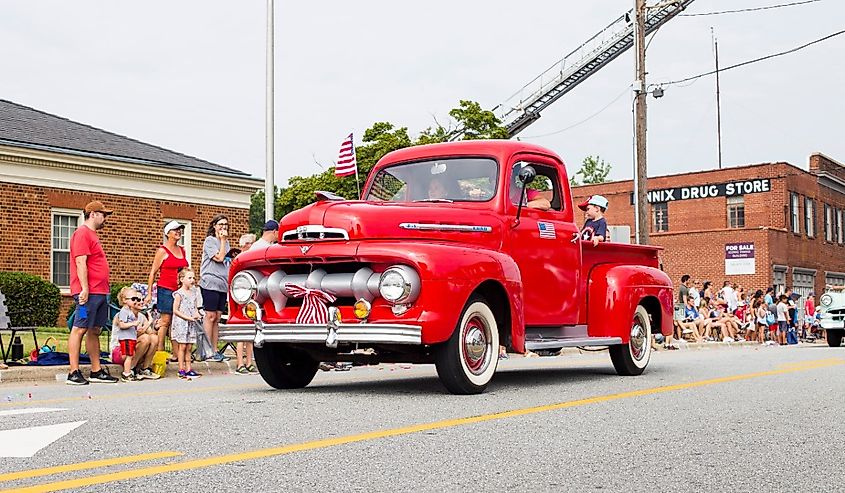 A red pickup truck driving through a small town fourth of July parade, Kernersville, North Carolina.