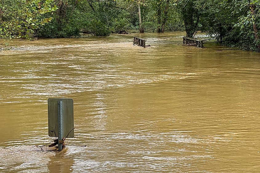 A sign and bridge are partially submerged as a local creek in Georgia floods from heavy rains dumped by Hurricane Helene. Via Shutterstock/Blulz70.