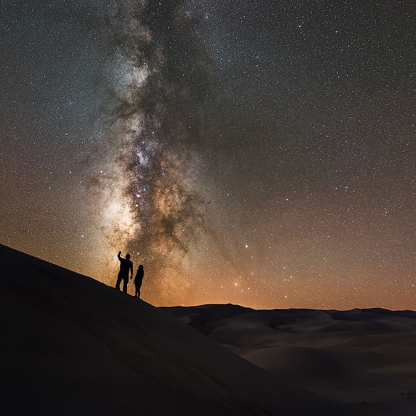 Stargazers appear silhouetted against the Milky Way Galaxy at Great Sand Dunes National Park.