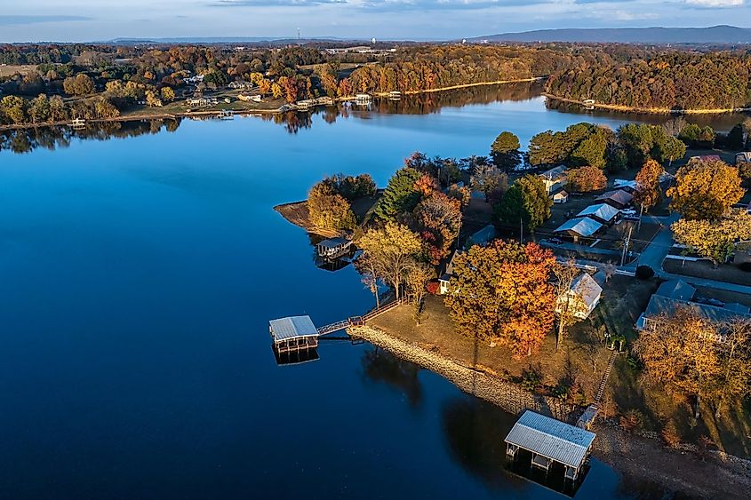 Aerial view of waterfront homes, boat docks and beautiful autumn foliage with mountains in the background on Tims Ford Lake in Winchester, Tennessee.