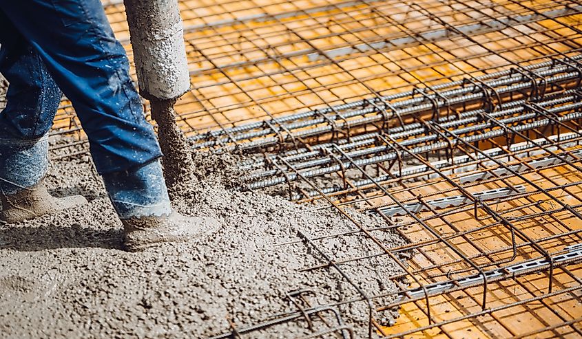 construction worker pouring cement or concrete with pump tube