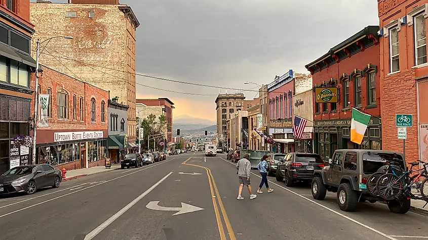A couple J-walks across Butte's historic downtown. A moody sunset compliments the rusty hues of its historic buildings.
