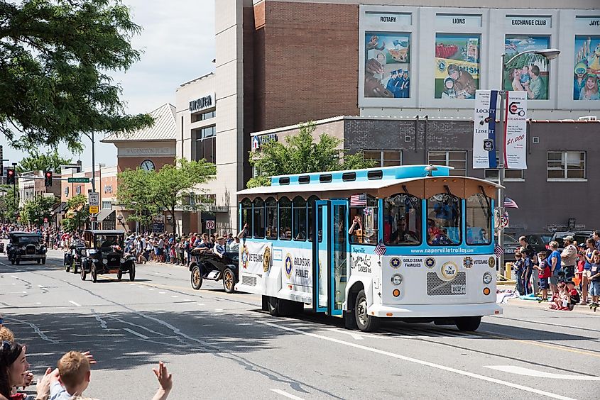 Memorial Day parade with trolley bus, veterans, classic cars and crowds in downtown Naperville, Illinois