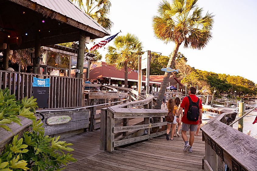 Murrells Inlet, South Carolina: The MarshWalk, located in the historic fishing village, with people walking on the wooden boardwalk next to restaurants, bars, and boats.
