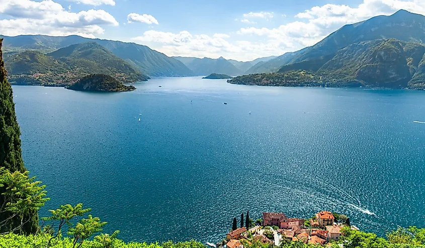 Panoramic aerial view of Lake Como from Varenna towards Bellagio with clear sky in summer and boats on the water.