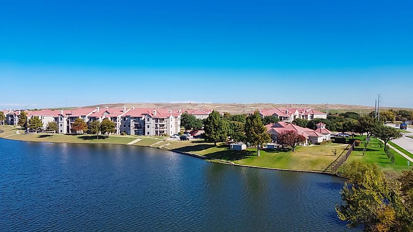 Aerial view of lakeside apartment complex with landfill trash hill in the background near Dallas, Texas