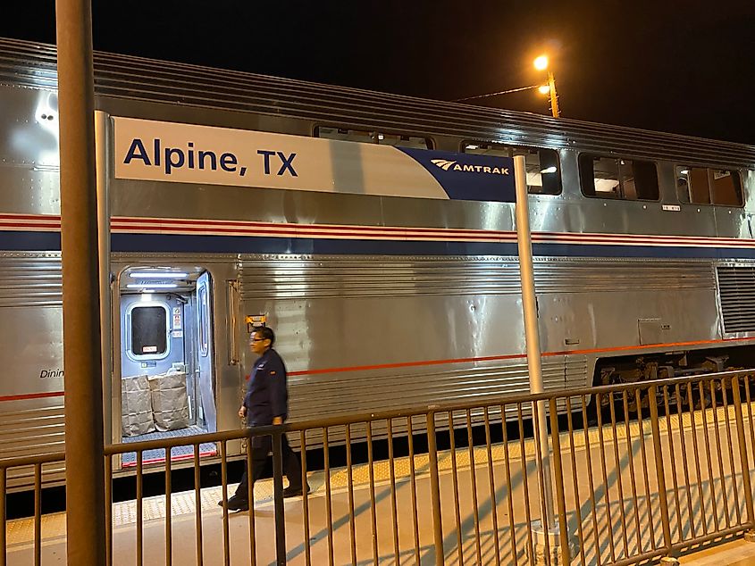 An Amtrak employee walks past a parked train at the Alpine, Texas station