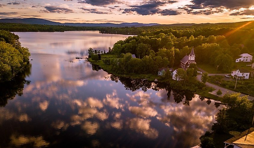 Sunset over Monson, Maine with waterfront homes and church