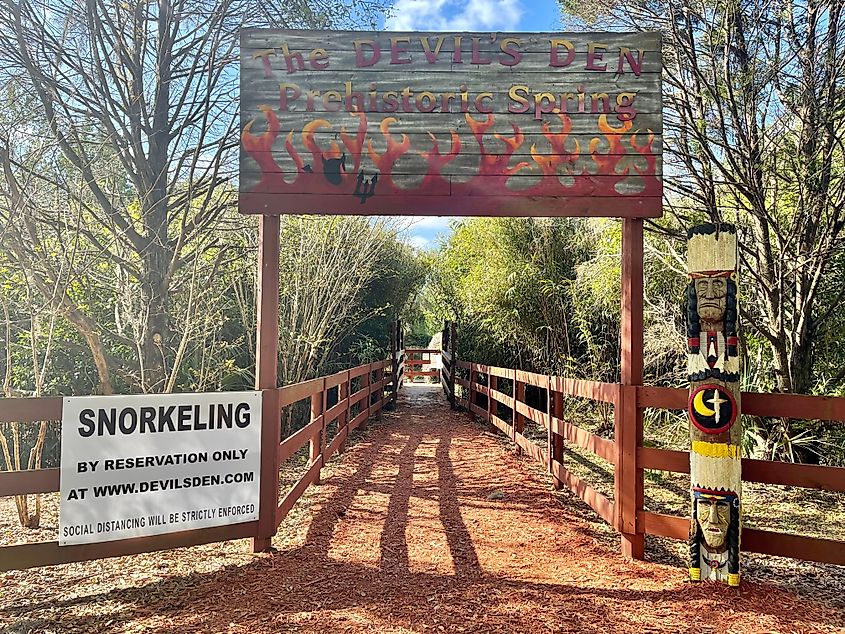 DEVIL'S DEN, WILLISTON, FLORIDA, USA - MARCH 28, 2022: A welcome sign with devil and pitchfork stands over the entrance to the sinkhole and dive resort at Devil's Den in Williston, Florida. 