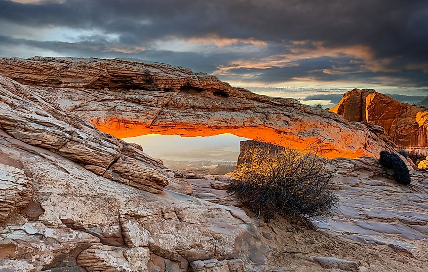 A dramatic sunrise casts a warm glow to the underside of Mesa Arch, Canyonlands National Park, Utah.