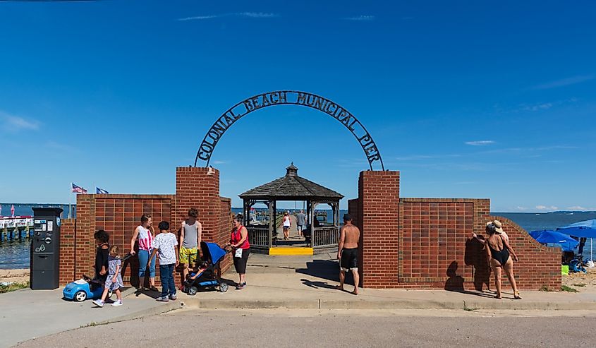 Families on vacation gather at the entrance to the Colonial Beach Municipal Pier on a late summer day under a blue sky, Colonial Beach, Virginia.
