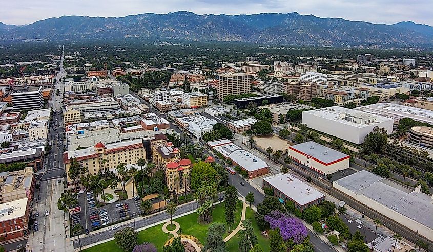 Aerial view of Pasadena California with blue sky and interesting cloud covers with buildings and purple trees in the cityscape and mountain range