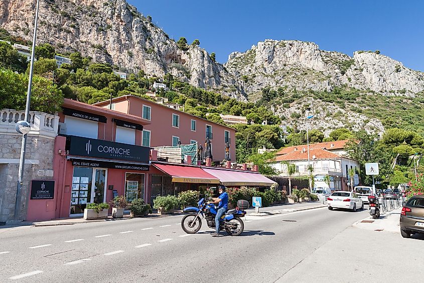 Eze, France: Avenue de la Liberte, street view with a motorcyclist and cars on the road