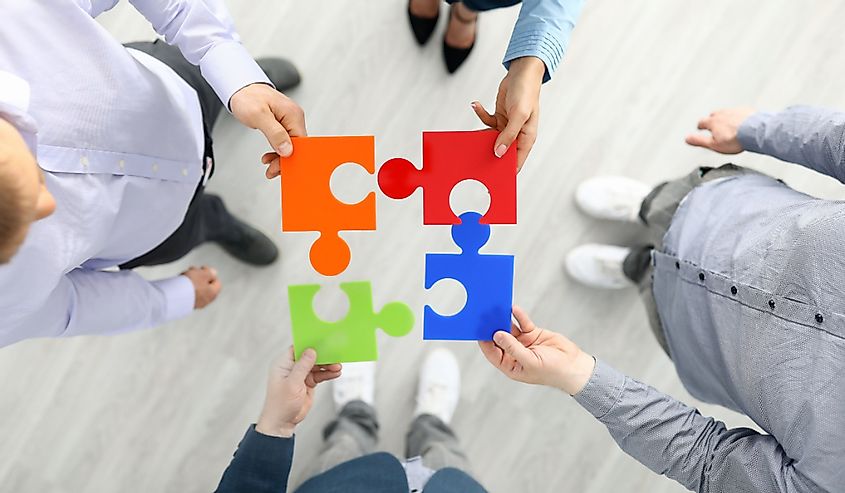 Group businees people hold color element puzzle top view background closeup. 